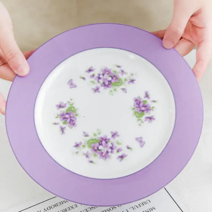 A delicate white porcelain plate with lavender rim and purple floral accents from the blue dream tea set