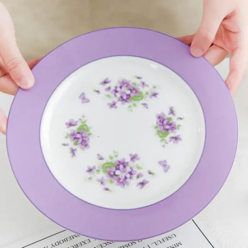 A delicate white porcelain plate with lavender rim and purple floral accents from the blue dream tea set