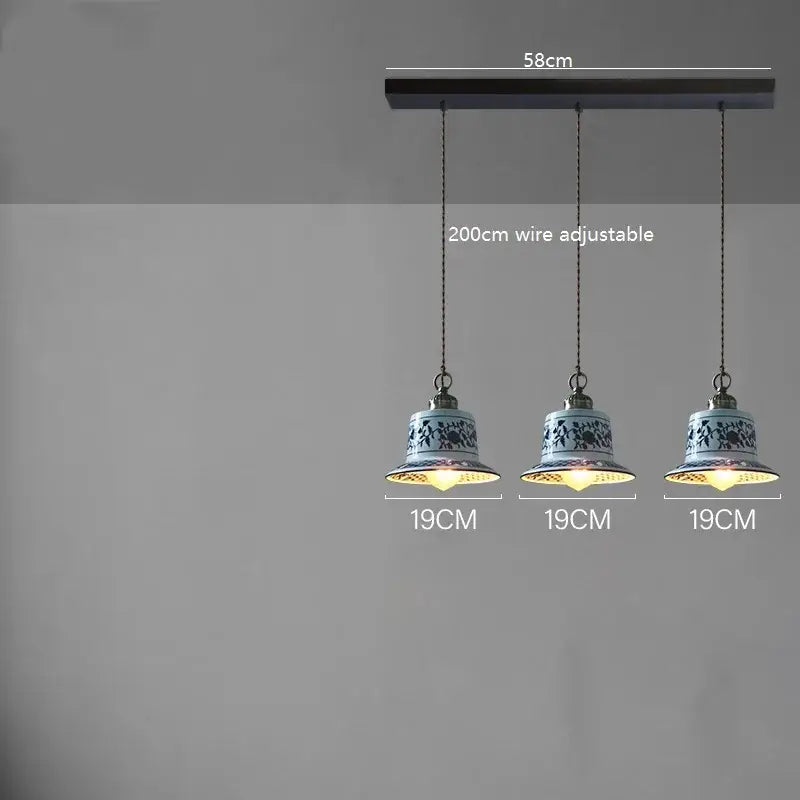 Three blue and white floral ceramic led pendant lamps hang from a dark wooden bar for dining room lighting decorbites ceramic led