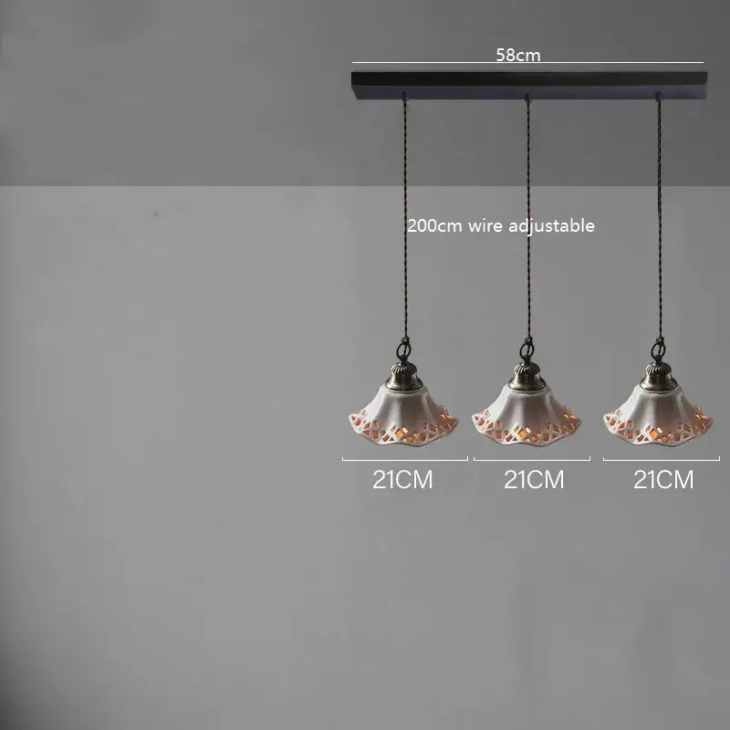 Three blush ceramic led pendant lamps with lace-like cutouts hang from a dark metal bar for dining room lighting decorbites ceramic led