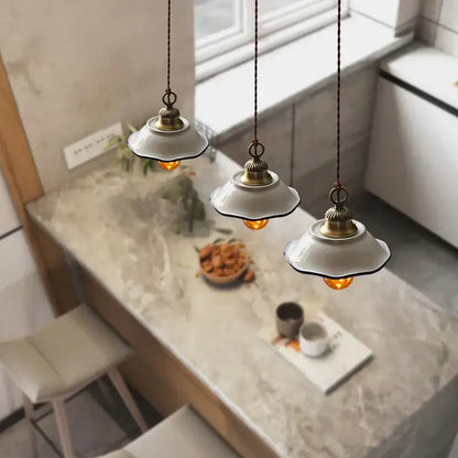 Three vintage-style decorbites ceramic led pendant lamps with white ceramic shades and brass accents above marble countertop