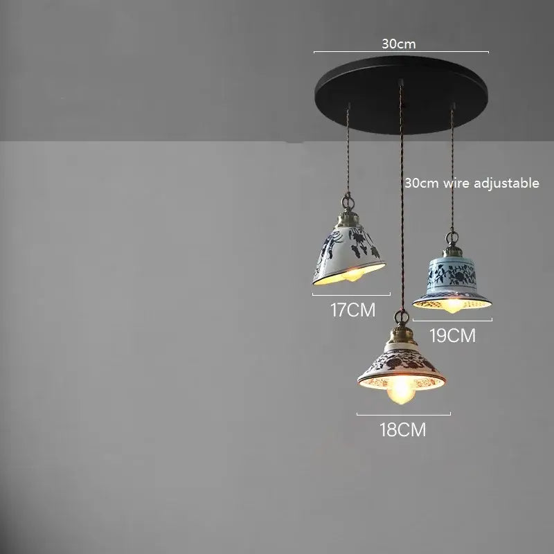 Three blue and white floral decorbites ceramic led pendant lamps hanging from black ceiling mount for dining room lighting
