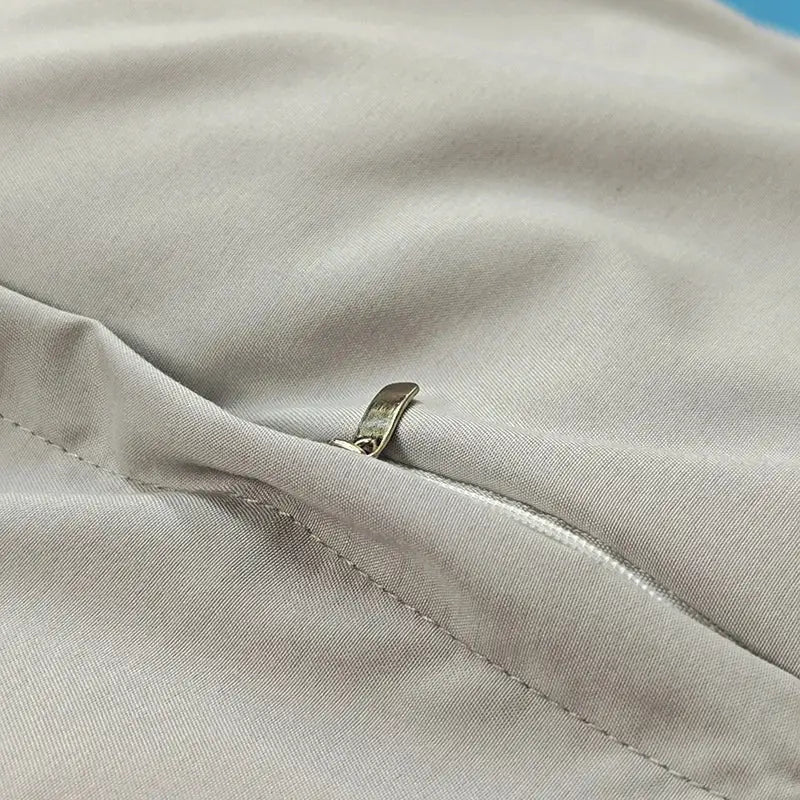A silver-toned zipper pull on the seam of decorbites blue satin jacquard duvet cover in light gray textured fabric