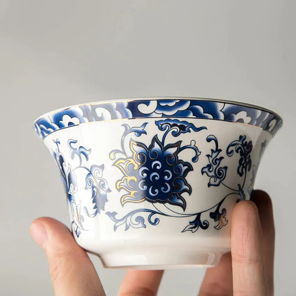 A white porcelain tea cup with blue and gold floral patterns from a blue floral white porcelain tea cup set