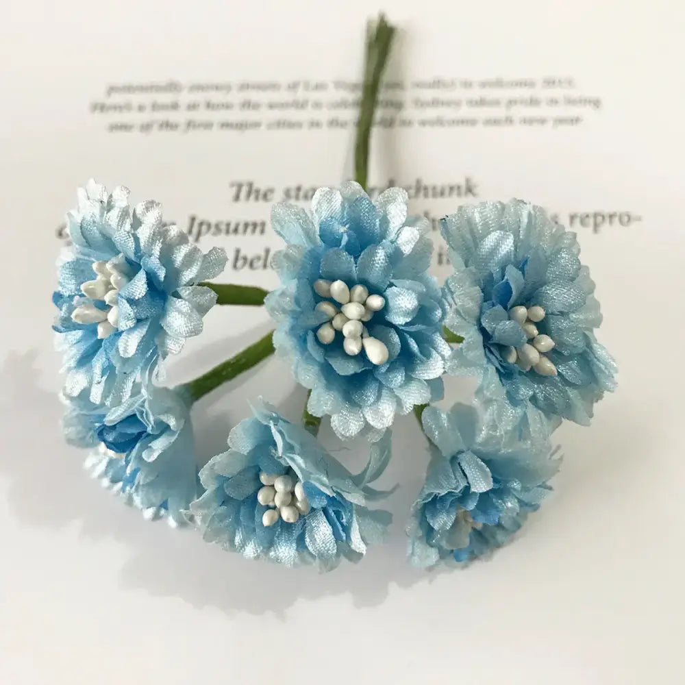 A delicate cluster of decorbites blue flower cherry fabric flowers with white bead centers and green stems for decor