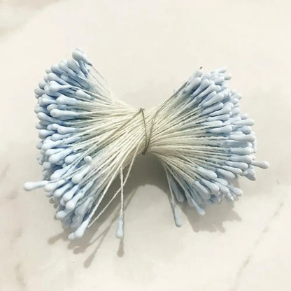 A bundle of light blue cotton swabs tied with a string resembling decorbites blue flower cherry stamen berries for decor