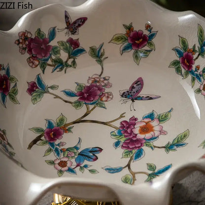 A delicate white ceramic flower pattern footed fruit bowl with decorbites blue flower motifs and a gold base for dining room use