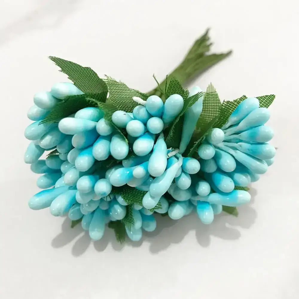 A cluster of light blue glossy paper blue flower stamen with green fabric leaves in a flower stamen berries bundle