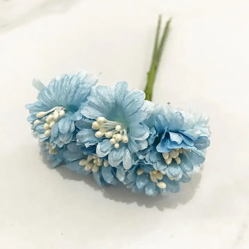 A bundle of delicate light blue flower stamen berries with white bead centers and green fabric stems for cake decor