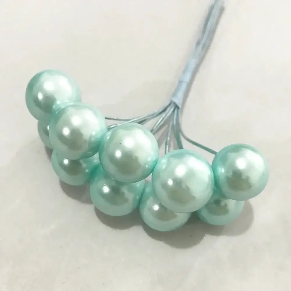 A cluster of light mint-green glossy faux pearls tied with thin wire in a flower stamen berries bundle for decor