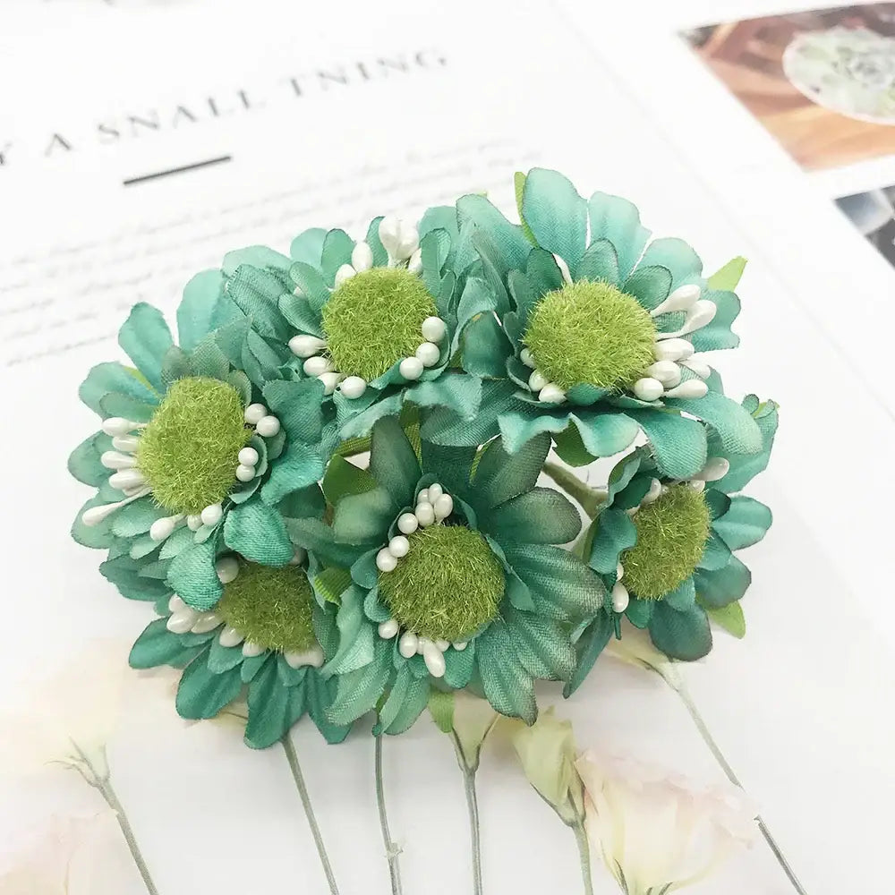 A cluster of teal fabric blue flower stamen daisies with fuzzy green centers and white bead flower stamen berries bundle