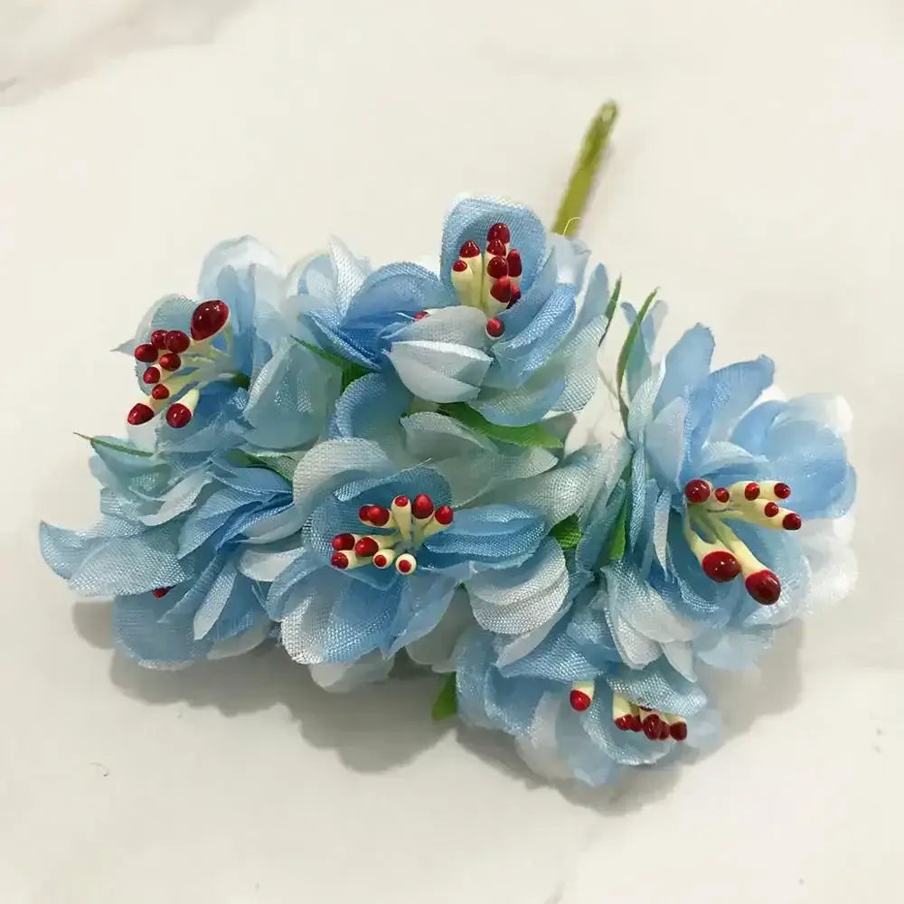 A delicate cluster of light blue fabric flower stamen berries bundle with red and yellow centers for kitchen cake decor