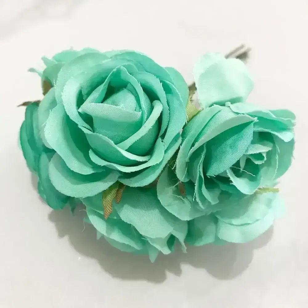 A delicate cluster of three mint green fabric roses with gold accents in a blue flower stamen berries bundle for cake decor