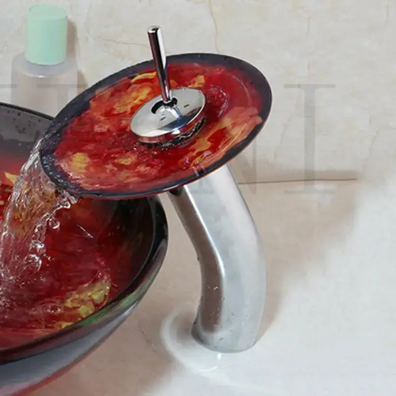 A sleek decorbites glass bathroom sink with vibrant red and black glass waterfall rocker handle faucet in chrome finish