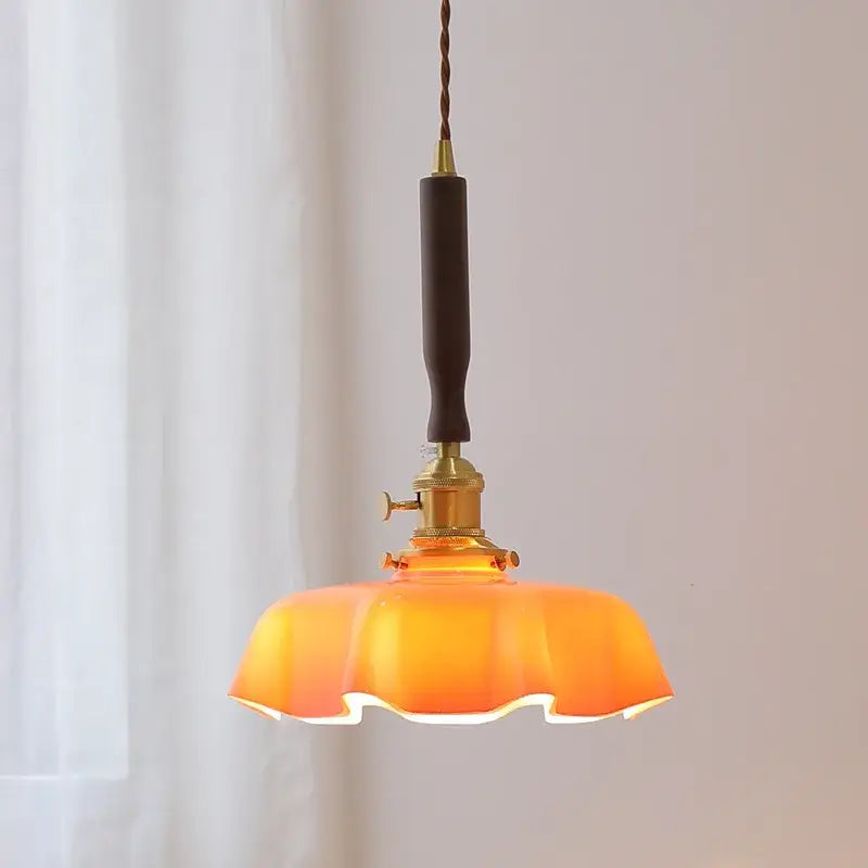Warm orange glass pendant lamp with brass fixture and dark brown cord complementing decorbites blue glass led design