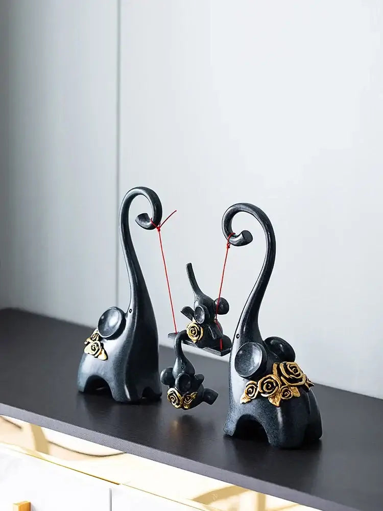 Black resin elephant family swing sculpture with gold rose accents and curved trunks for living room decor