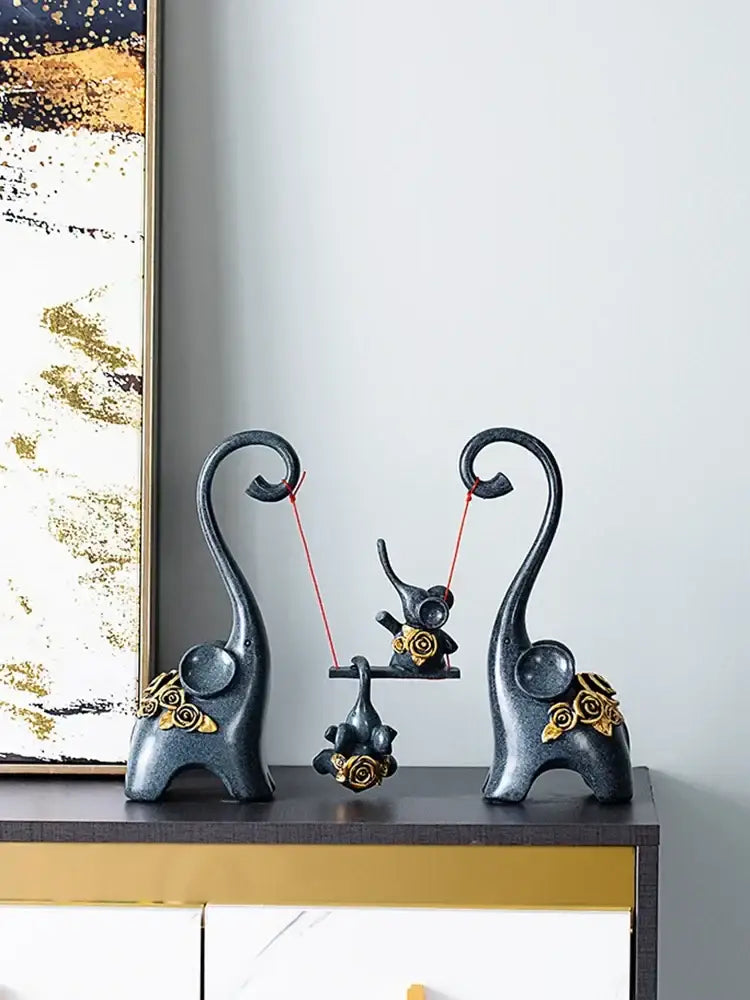 Black resin elephant family swing sculpture with gold rose accents and curved trunks for living room decor