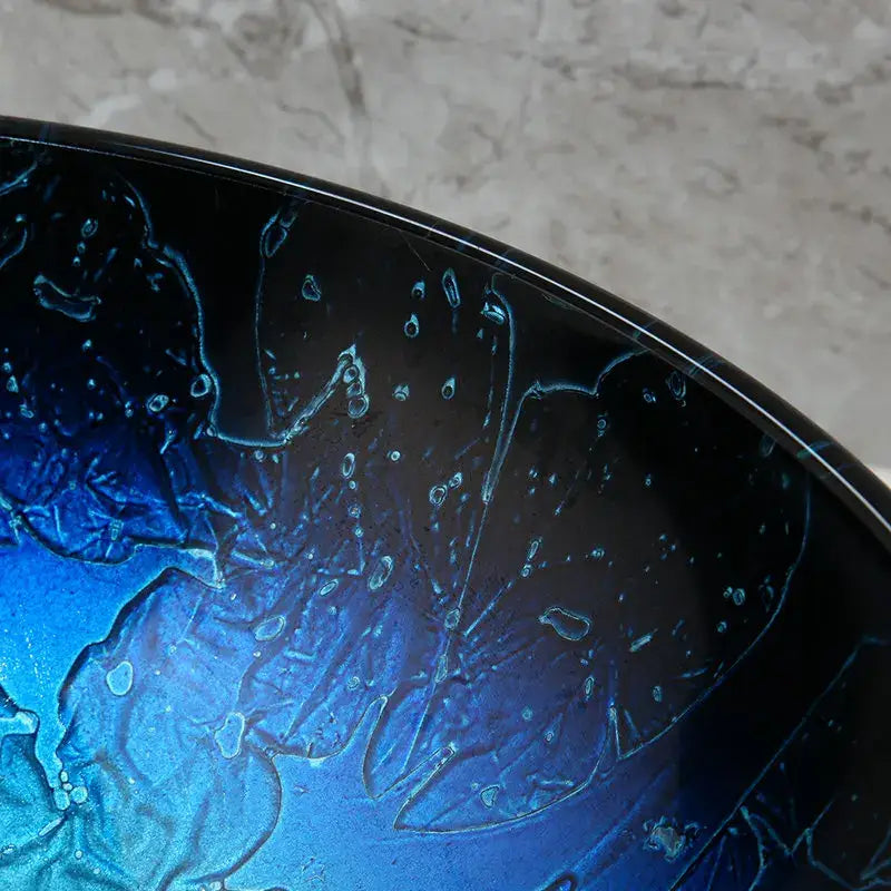 Glossy deep blue tempered glass basin sink set with abstract swirling pattern and waterfall faucet for bathroom use