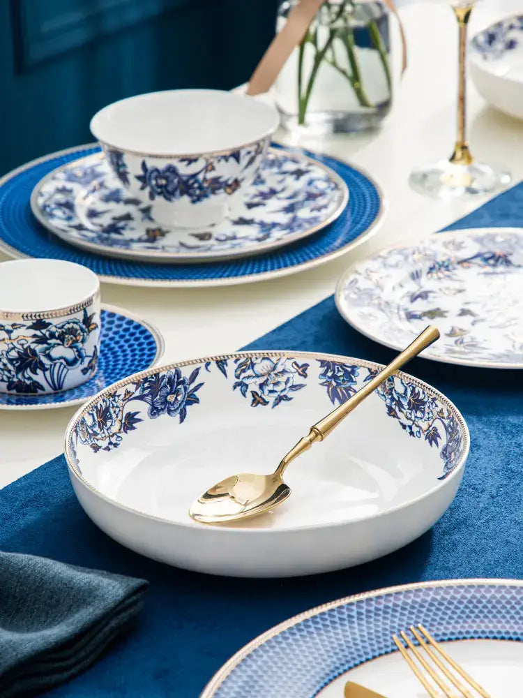 White ceramic bowl with blue floral pattern and gold rim with matching golden spoon from decorbites blue lotus dinnerware