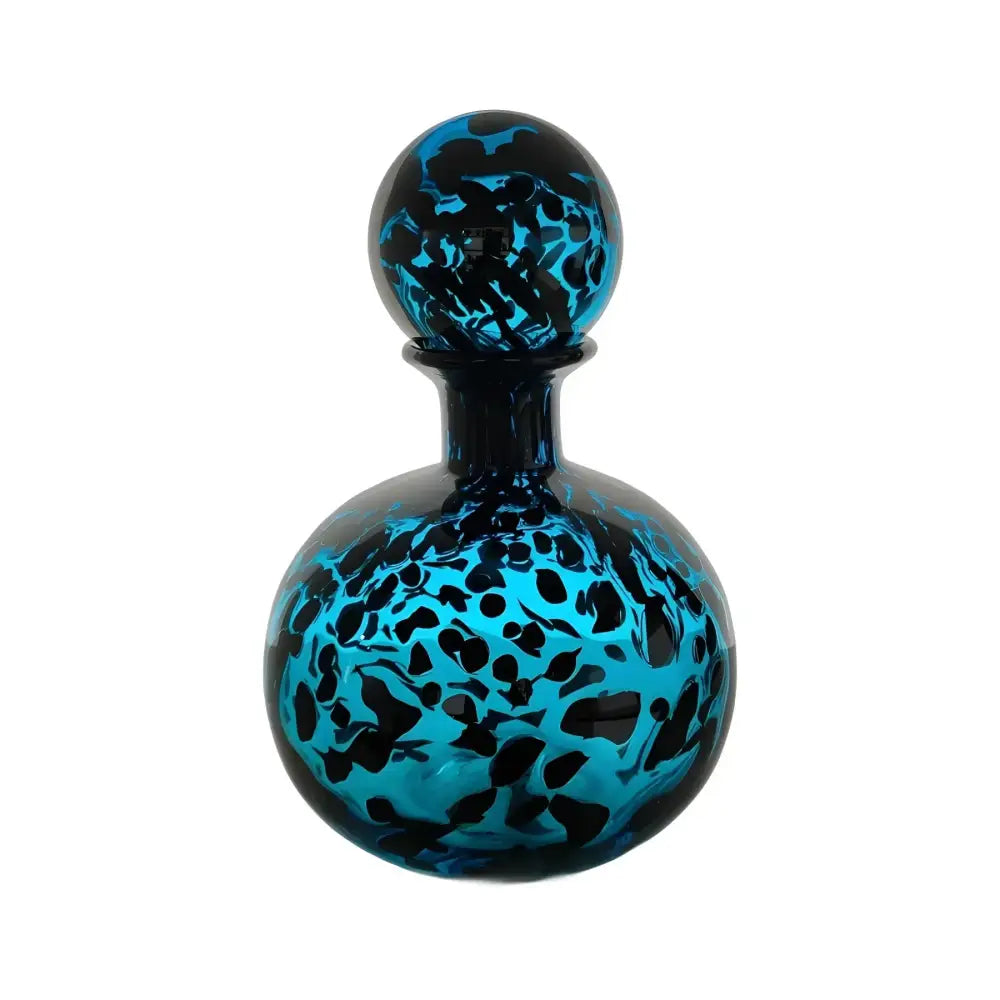 A vibrant blue glass perfume bottle with a spherical black and teal marbled stopper for decorbites leopard print decor
