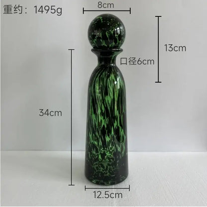 A tall slender green glass decanter with swirling marbled pattern and rounded stopper for decorbites leopard print decor