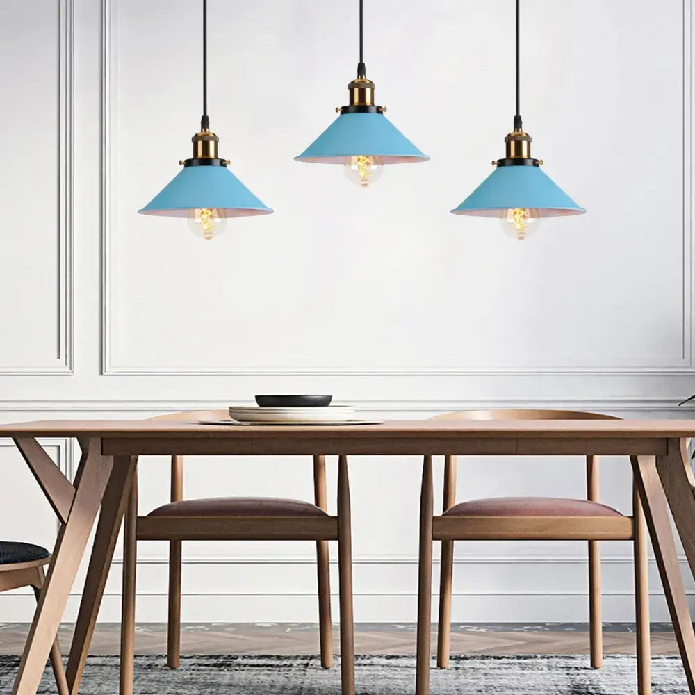 Three blue matte metal nordic pendant lights with brass fixtures hang above a wooden dining table decorbites blue nordic pendant