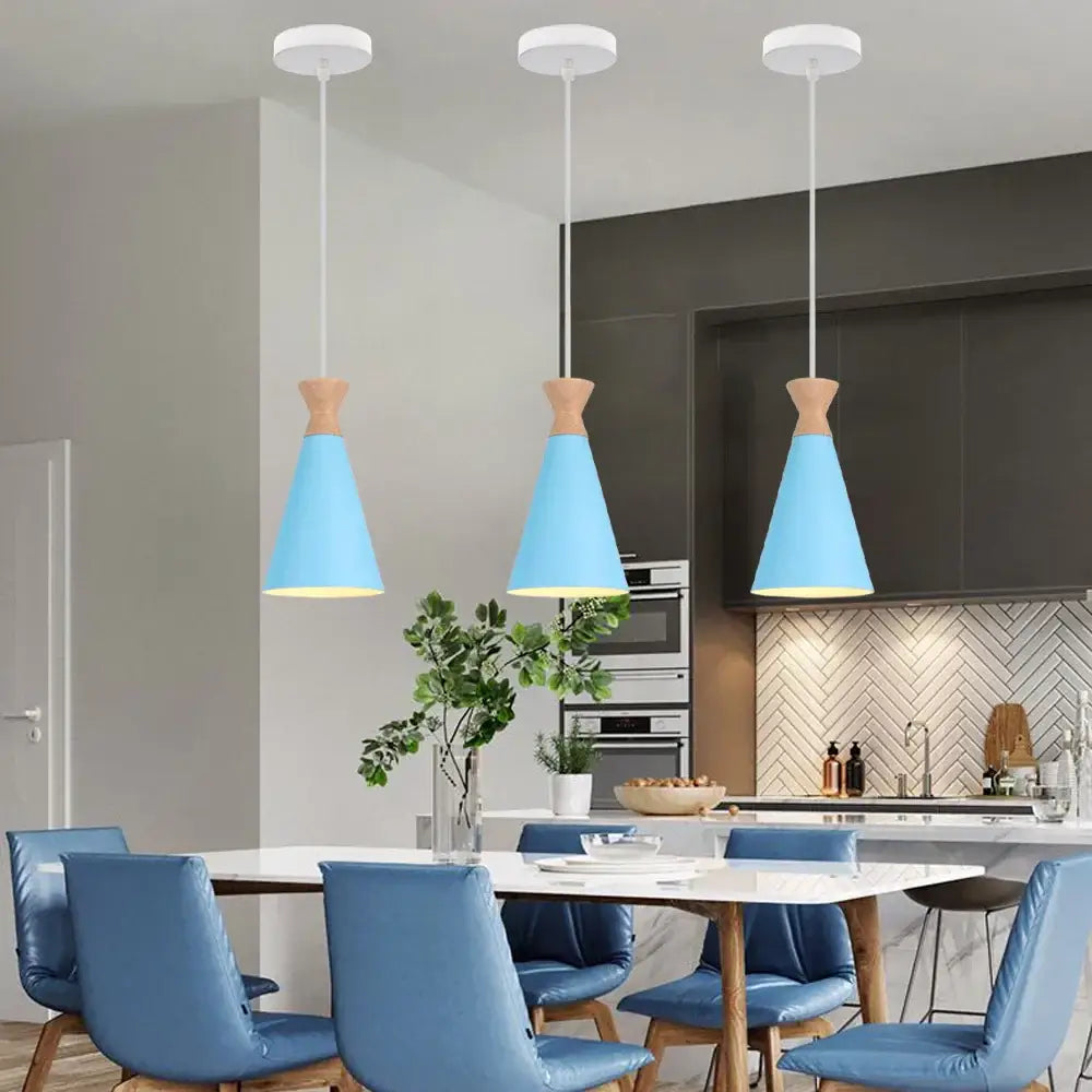 Three blue nordic pendant lights with matte metal conical shades and brass fixtures hang above a dining table