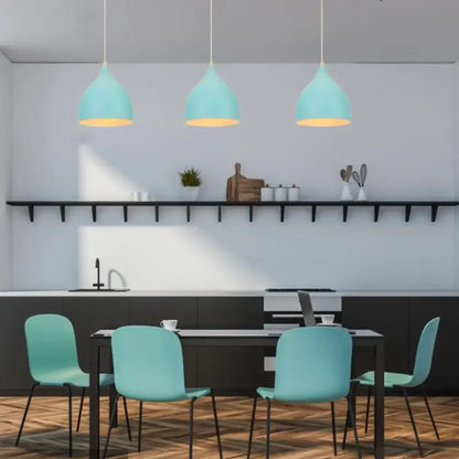 Three teal blue nordic pendant lights with matte metal and brass fixtures hang above a dining table for decorbites