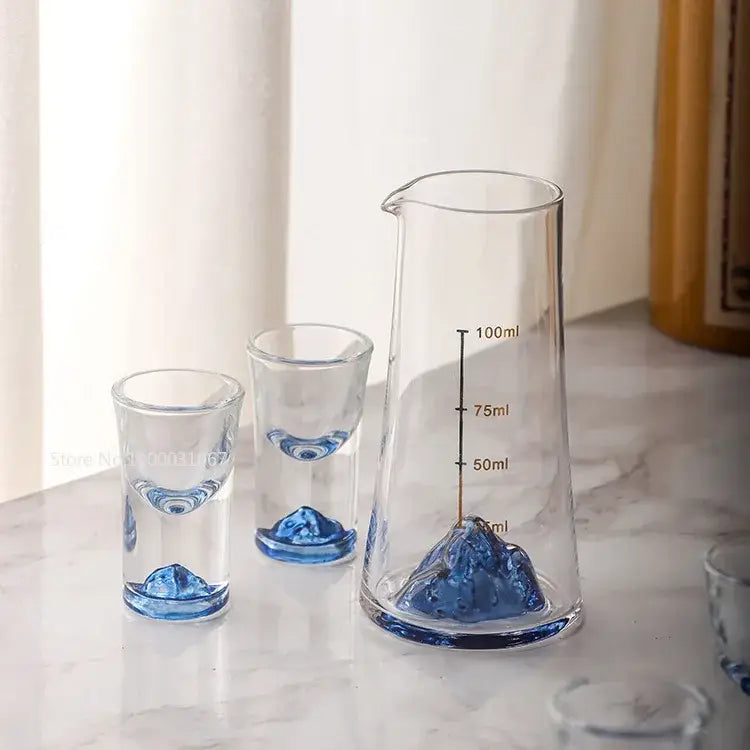 Clear glass decorbites blue sake pitcher and two matching blue sake glass ice shot glasses with sculpted mountain bases
