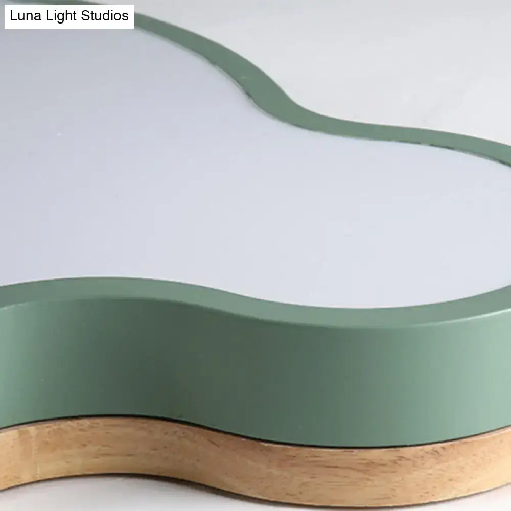 A sleek flush mount ceiling lamp with a matte sage green top and natural wood base for kids bedroom