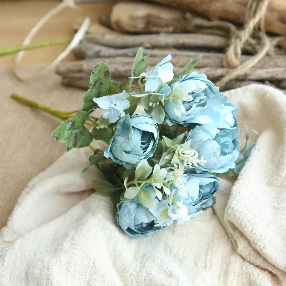 A delicate bouquet of light blue silk fake flowers featuring blue peony and tea rose for home garden decor
