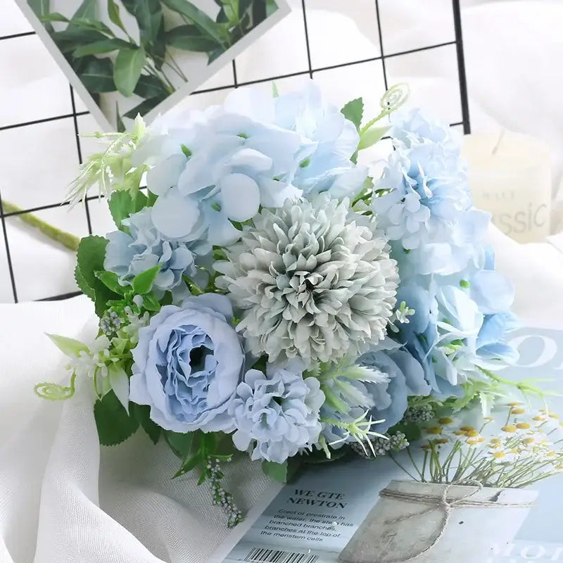 A delicate bouquet of silk fake flowers featuring blue peony hydrangeas and tea rose blooms in soft blue and pale green hues