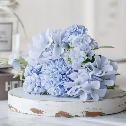 A delicate bouquet of light blue silk fake flowers featuring hydrangeas and subtle green stems for home decor