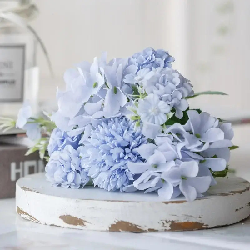 A delicate bouquet of light blue silk fake flowers featuring hydrangeas and subtle green stems for home decor