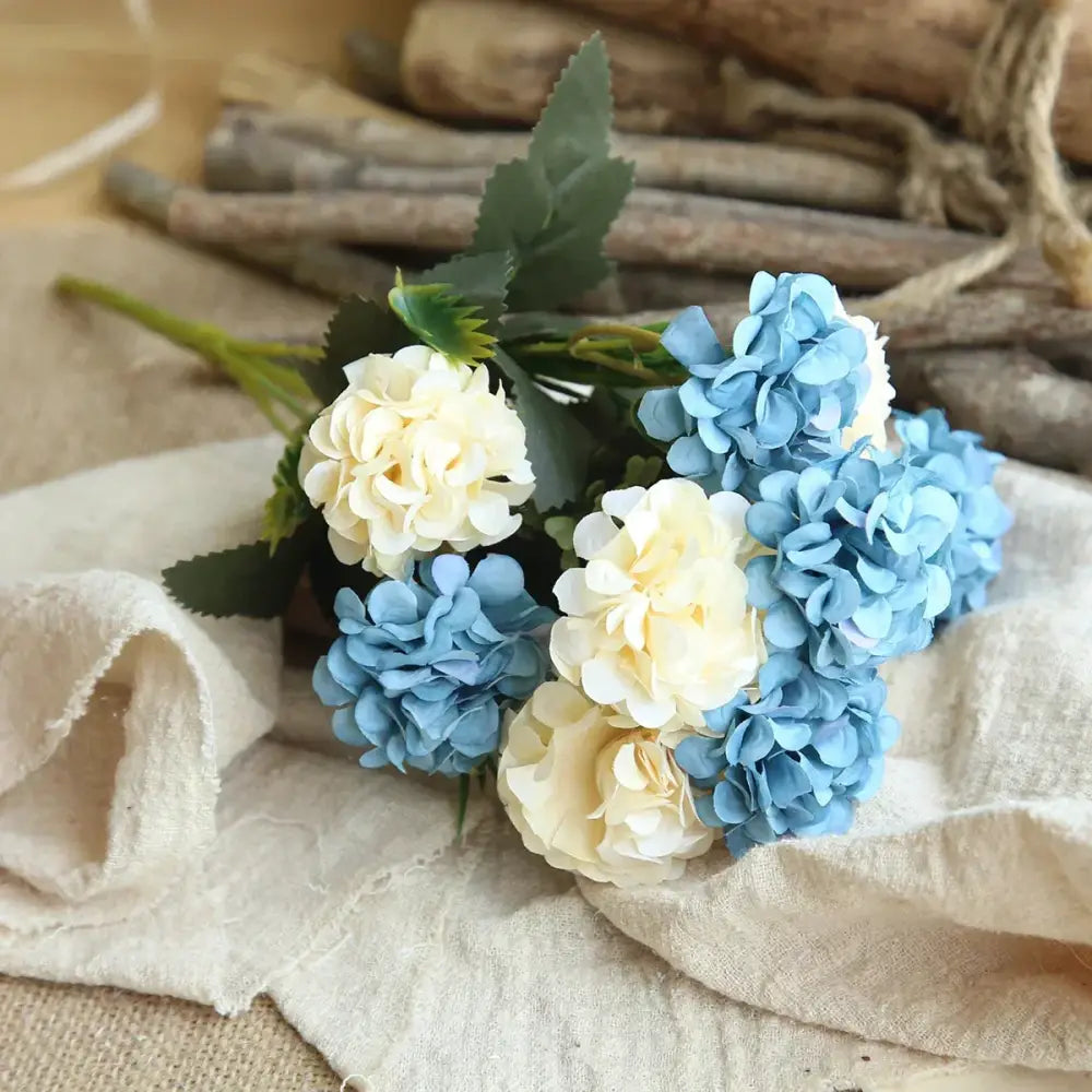 A delicate bouquet of silk fake flowers featuring blue peony and tea rose in soft blue and creamy white for home decor