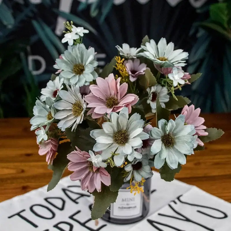 A delicate bouquet of silk fake flowers featuring blue peony and tea rose in pastel shades arranged in a glass jar