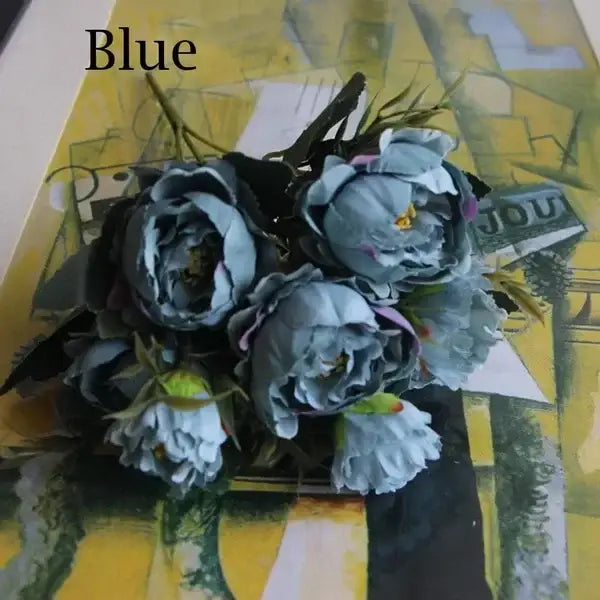 A bouquet of silk fake flowers featuring blue peony and tea rose with dark green stems for home garden decor