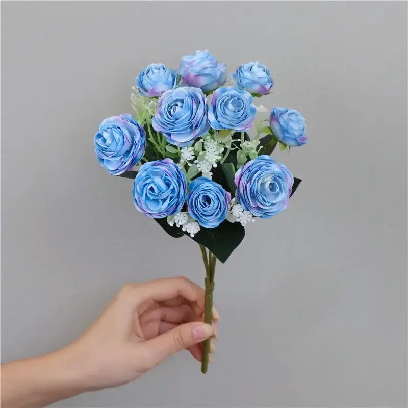 A bouquet of silk fake flowers featuring blue peony and tea rose with purple gradients and white filler blooms