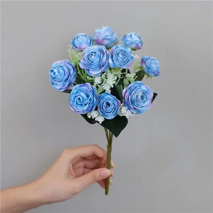 A bouquet of silk fake flowers featuring blue peony and tea rose with purple gradients and white filler blooms