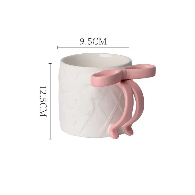 A white ceramic bowknot ceramic mug with a pink bow-shaped handle and subtle diamond texture from decorbites saucer set