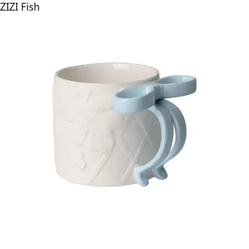 A white ceramic bowknot ceramic mug with a light blue handle and textured design from the decorbites saucer set