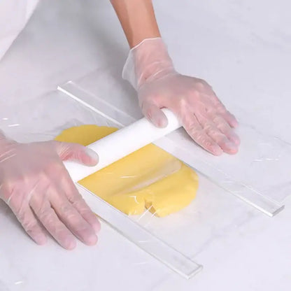 A white rolling pin flattens yellow dough inside a bag showcasing the rolling balance ruler with wood handles