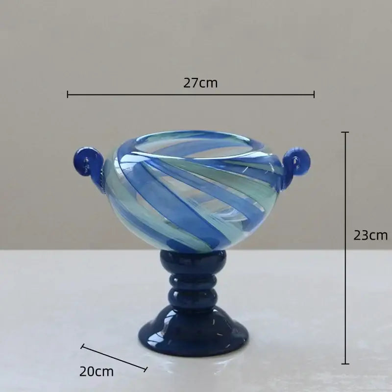 Blue striped transparent glass vase with blue and white swirl design and spherical handles on dark navy pedestal base