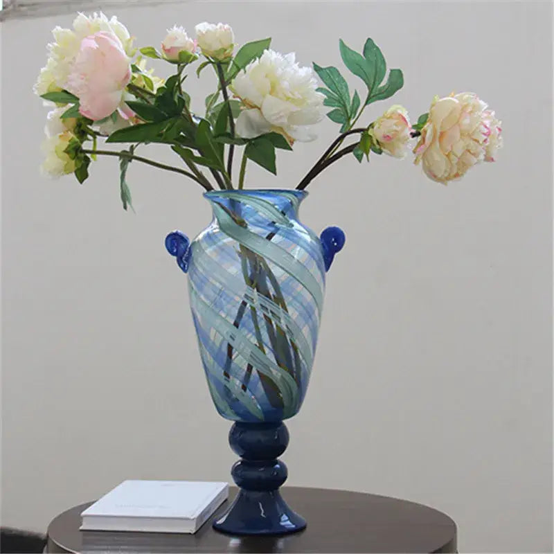 A tall elegant decorbites blue striped transparent glass vase with swirling patterns and small side handles for living room decor