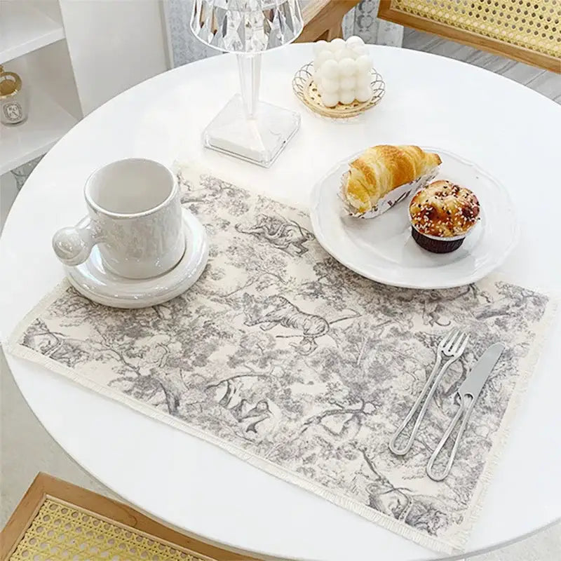 Beige cotton linen meal mat with delicate gray toile animal and foliage pattern and soft fringe for dining decorbites cotton linen