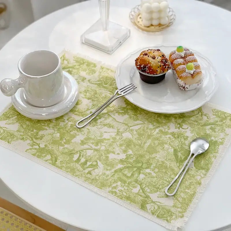 A delicate sage green and cream toile-patterned cotton linen meal mat with frayed edges from decorbites cotton linen collection