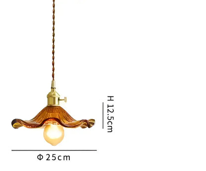 A warm amber glass decorbites pendant light with brass fixture and twisted cord for bedroom decor