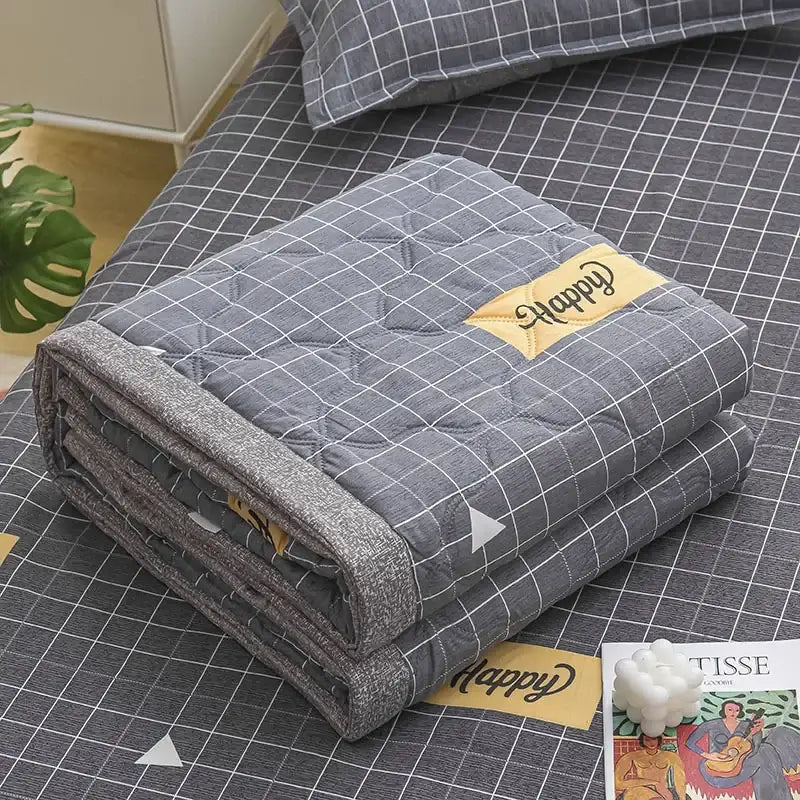 Gray quilted blanket with subtle grid pattern and yellow happy patch featured in decorbites daisy print quilt collection