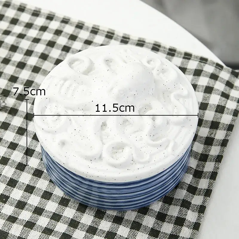 Stack of white ceramic marine life plates with blue rims and embossed octopus design for decorbites ceramic marine use