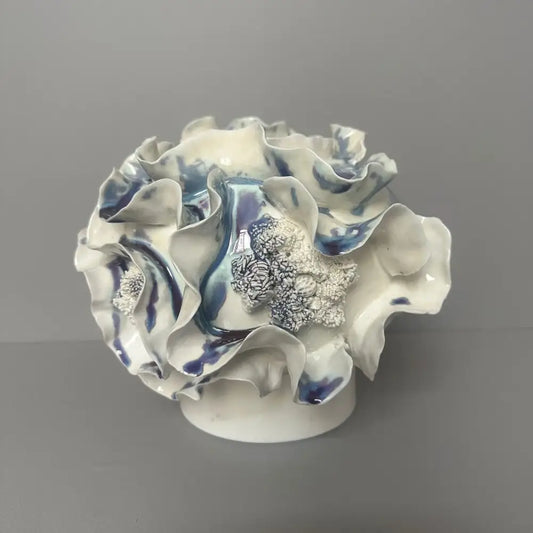 A delicate blue and white decorbites handmade porcelain fold pattern vase with ruffled glaze petals and a silver centerpiece